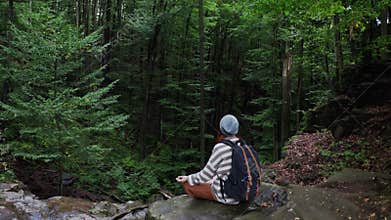 Tiurist woman on mountain excursion high on cliff looking the distant beautiful landscape forests. meditation in forest