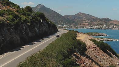 Top Aerial View Of A Red Car Drive On The Road Near Sea. Aerial Drone shot of cars driving on beach and coast rooad.