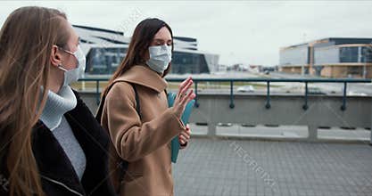 Social activism during coronavirus crisis. Two Caucasian female doctors walk on empty city street in medical face masks.
