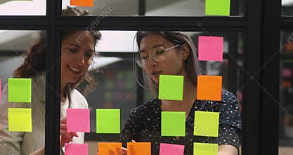 Multiethnic young businesswomen managing working process together at kanban board.