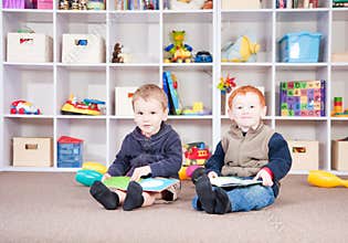 Smiling children reading kids books in play room