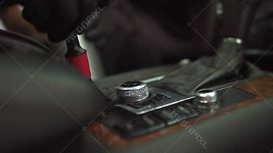 Car wash, a man cleans the car button with a brush from dust, in black the glove smoothly cleans the dirt of the