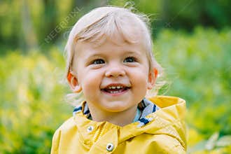 Portrait of cute baby boy in yellow raincoat. Child smiling. Love, care, attachment, family, children concept.