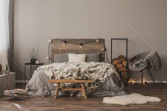 Copy space on empty grey wall of stylish bedroom interior with wooden accents and king size bed