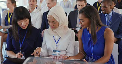 Women in the audience at a business seminar talking