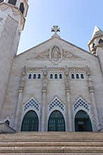 Big white cathedral with cross and three doors and stairs. Catholic church with open door. Religion and faith concept. 