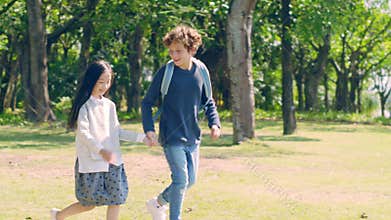 Little asian girl and caucasian boy walking in park