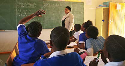 Female teacher and young pupils working in class 4k