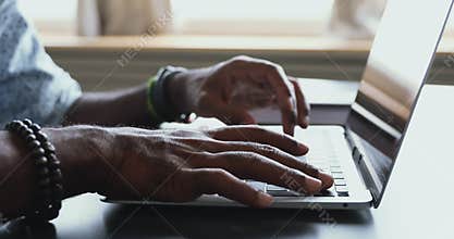 Male african american user typing on laptop at table, closeup