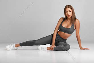 Sexy fitness woman. Beautiful athletic girl, isolated on the gray background