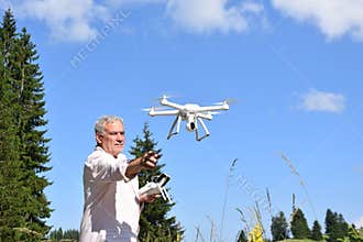 Senior man navigates unmanned aerial vehicle among nature