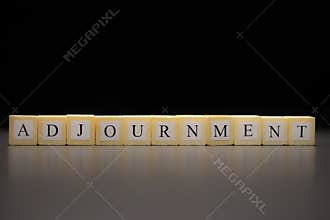 The word ADJOURNMENT written on wooden cubes isolated on a black background
