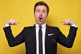 Positive young man with mustache smiling and pointing at himself with index fingers. Handsome