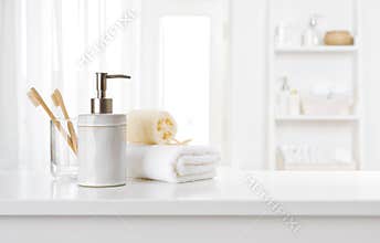 Soap dispenser, toothbrushes and white towel on bathroom counter interior