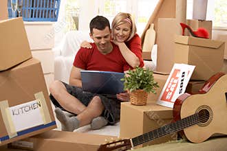 Happy couple looking at computer in new house