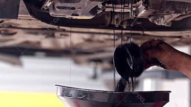 Replacing the Worn Black Oil Filter in a Car Engine at the Repair Shop