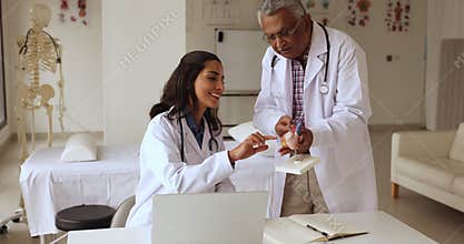 Cardiologist teaching young intern at meeting in hospital