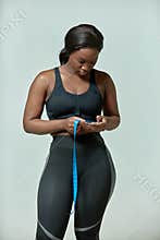 Sad african american woman measuring waistline size using tape measure. Weight loss, slimming and obesity concept