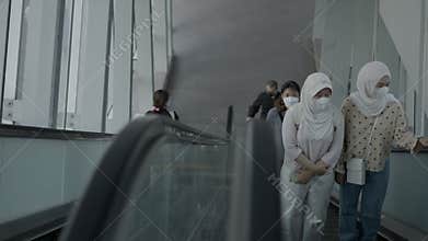 Two girls wearing hijab are coming up the escalator. The video was made from above