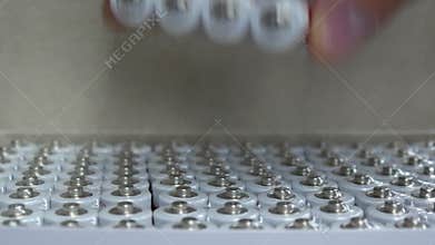 Close-up of many packs of AA batteries in a box and a male hand takes one