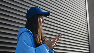 Side View of the Caucasian Lady Looking Around, Using Smartphone while Standing on City Street. Cute Woman Phone User