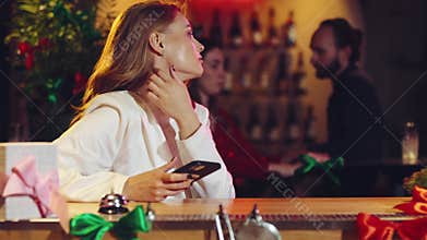 Young elegant woman sitting on bar, looking on phone and waiting for friends or boyfriend to come. Lonely date