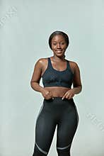 Smiling young african american girl wearing sportive clothes enjoying her shape and big size. Body positive, self love