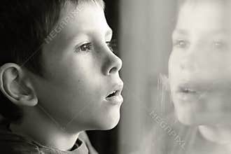 Young boy in thought with window reflection