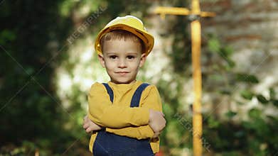 Little builder in helmet. Child dressed as a workman builder. Portrait little builder in hardhats. Caucasian industry