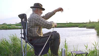 old handsome bearded man in hat and checked shirt untangling rod