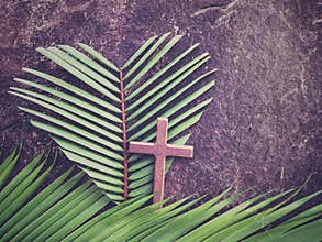 Lent Season,Holy Week and Good Friday concepts - image of wooden cross and heart shaped of palm leaf in purple vintage background.