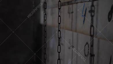 The chains are hanging on a gray wall with numbers and dashes in the quest room.