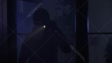 theft, man in a balaclava enters a room at night with a flashlight in search of valuables
