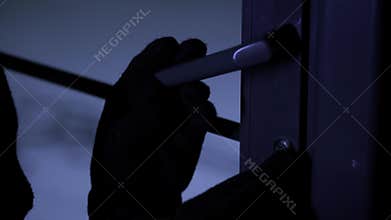 apartment break-in, man in gloves with master key in hands opens door lock at night, close-up
