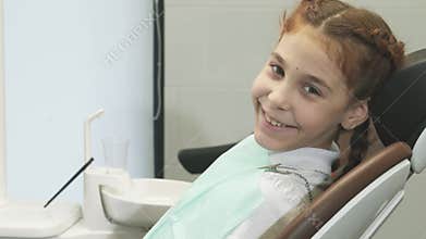 Adorable little girl smiles brightly at the camera in a dental office
