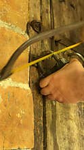 Man cutting padlock with hacksaw. Vintage wooden door in brick wall. Close-up. Vertical video