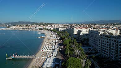 Drone flying over the beach and resorts with trees in Cannes City, France