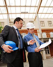 Architect talking to investor over the blueprints