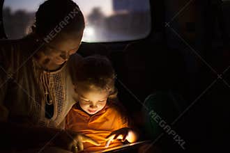 Mother and son with pad during car travel at night