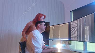 Programmers working at night analyzing code on monitors in a modern office