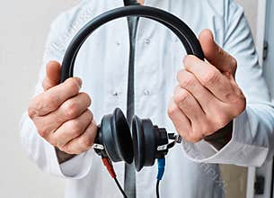 Audiometer headphones in hands of audiologist for audiometry test, close-up. Hearing test with audiometer headset
