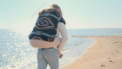 Man carries joyful woman on his back during lakeside walk.