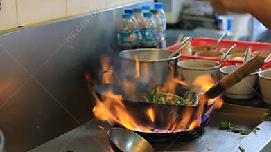 Professional chef in a commercial kitchen cooking flambe