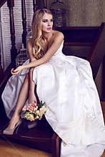 Beautiful bride with blond hair in elegant wedding dress with bouquet