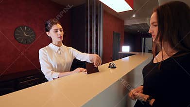 Attractive woman checking in hotel reception lobby. Travelling on vacation carrying luggage.