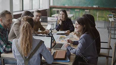 Female team leader brings documents to creative business team. Mixed race group of people meeting in modern office.