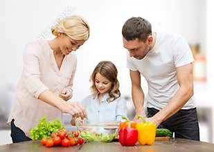 Happy family cooking vegetable salad for dinner
