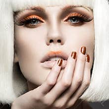 Beautiful girl in a white wig, with gold makeup and nails. Celebratory image. Beauty face.