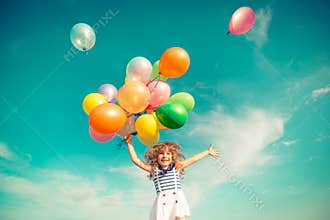 Child jumping with toy balloons in spring field