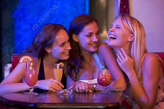 Three young women sitting at a table and laughing